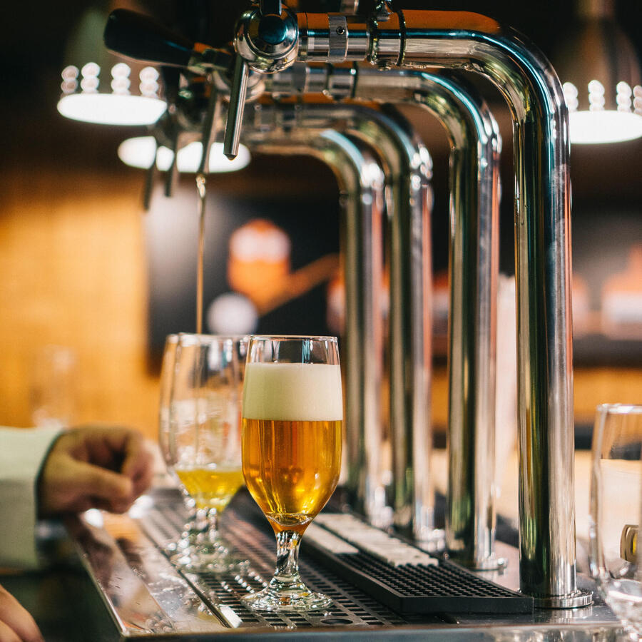Two glasses of beer being poured under a pump